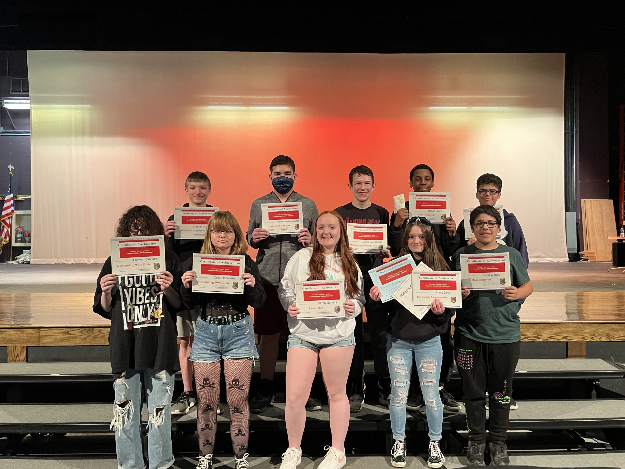 Students lined up in two rows holding certificates