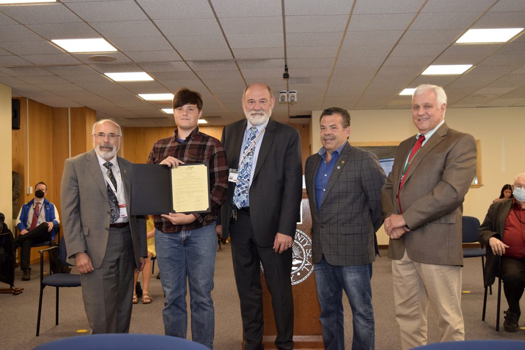 Five individuals standing next to one another, one individual with a certificate